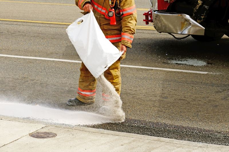 firefighter pouring absorbent material on a fuel spill